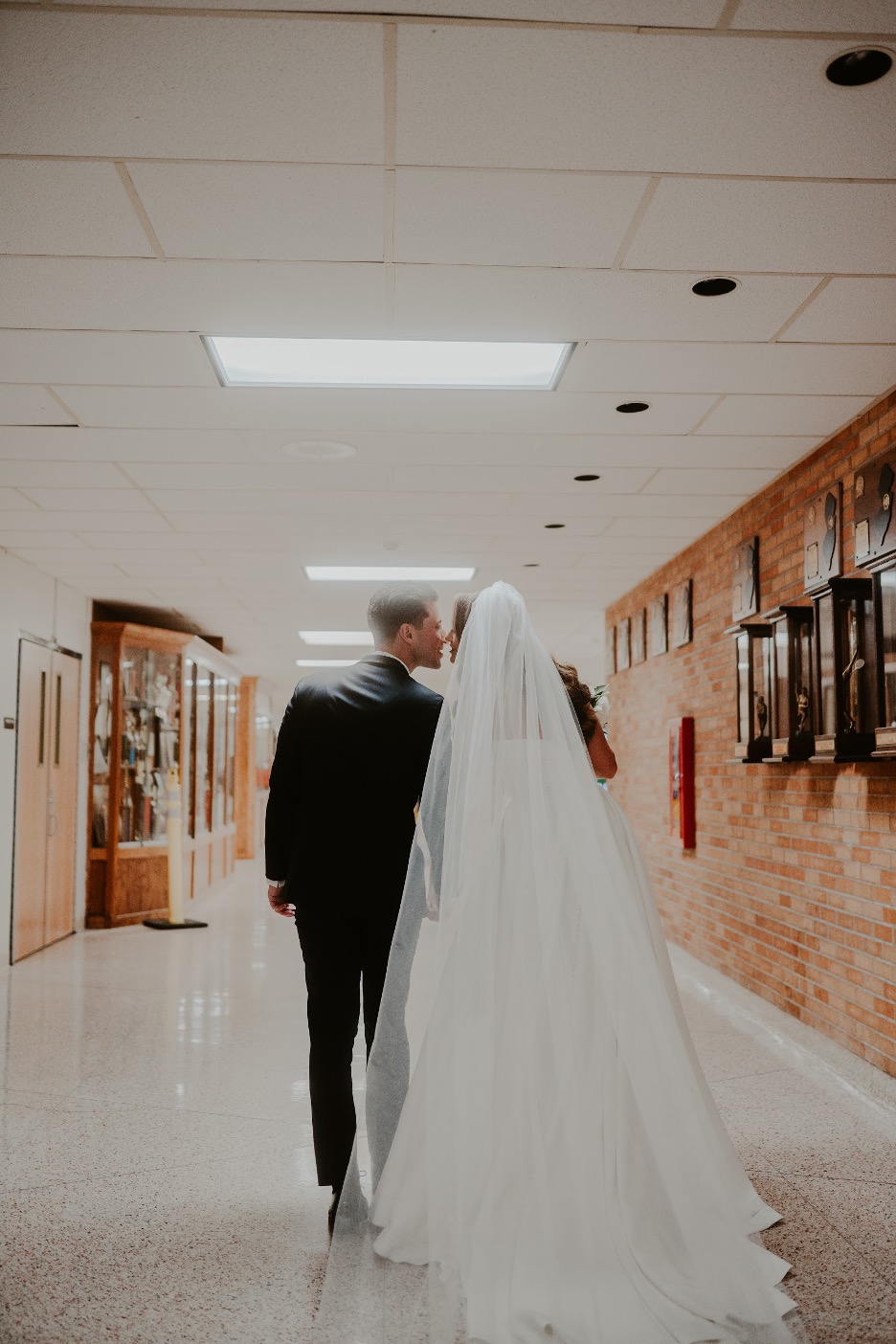 The bride and groom make a pitstop at their high school, where they met, on their wedding day.