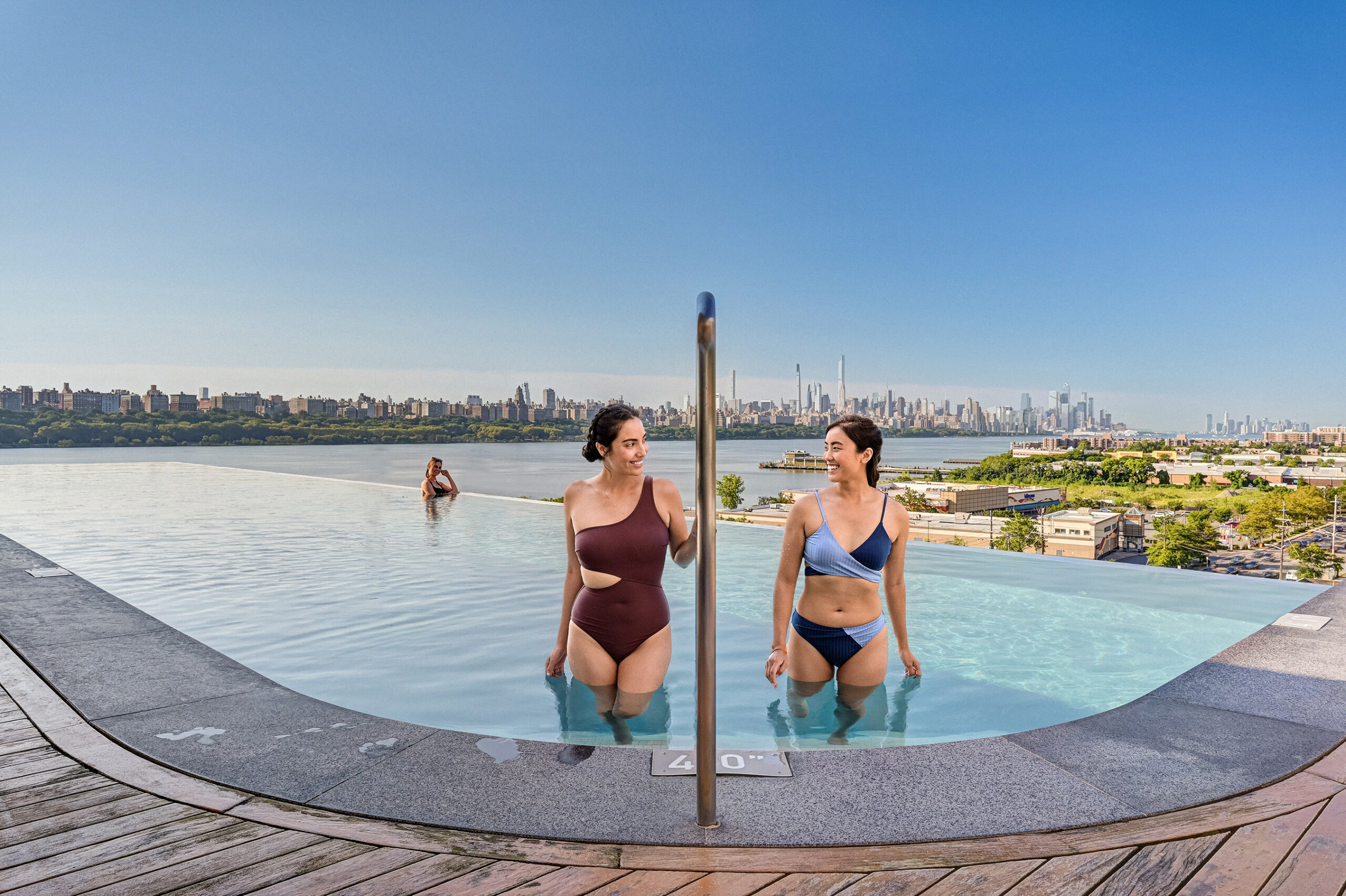 Two women in an infinity pool overlooking NYC at SoJo Spa Club, a fun New Jersey bachelorette party spot.